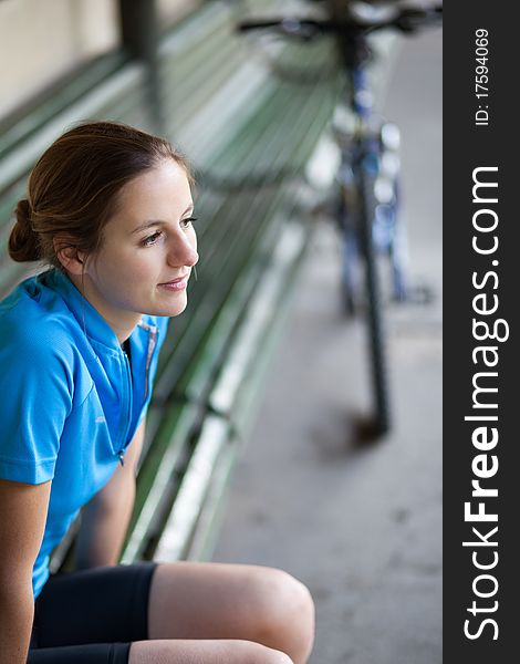Portrait of a pretty female biker outdoors resting on a bench (shallow DOF)