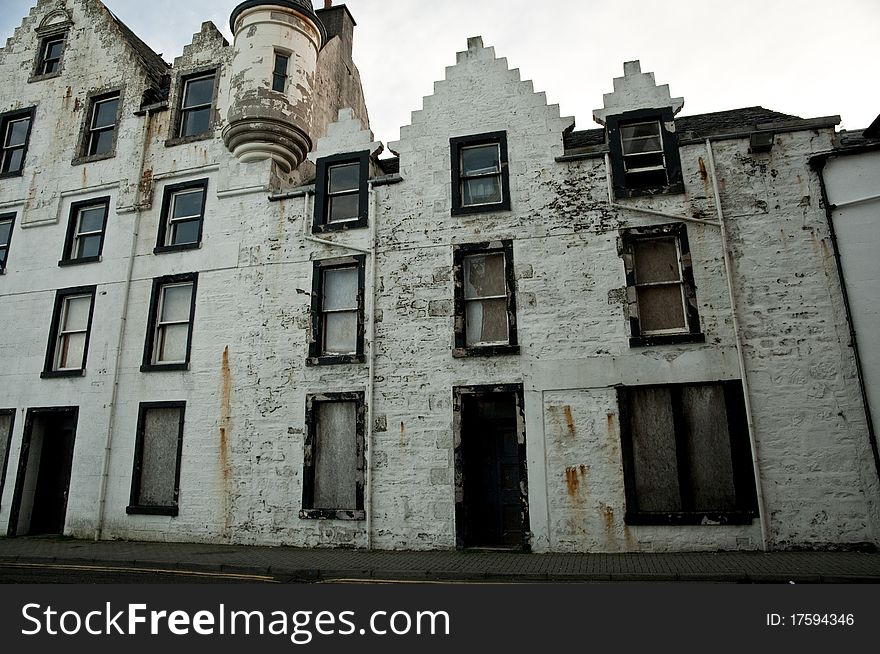 Abandoned historic building with windows boarded up and peeling paint, Scotland