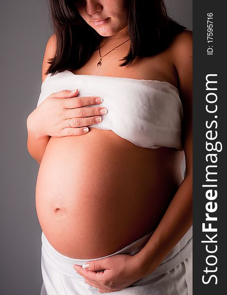 Beautiful pregnant woman staing on grey background, close up
