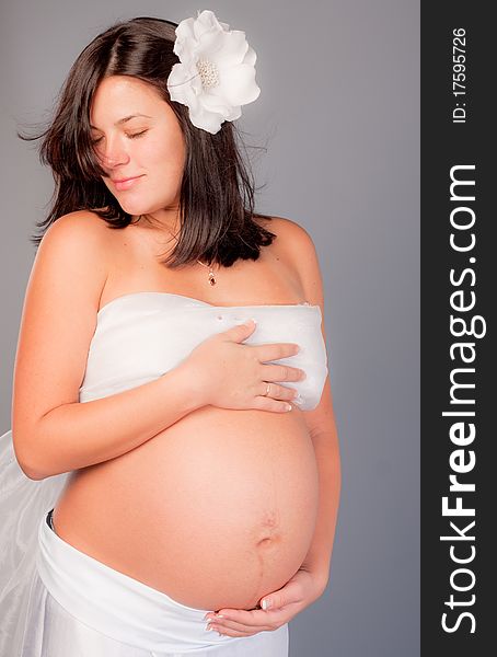 Beautiful pregnant woman staing on grey background, close up