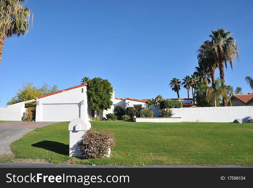 House surrounded by trees and grass with blue sky.