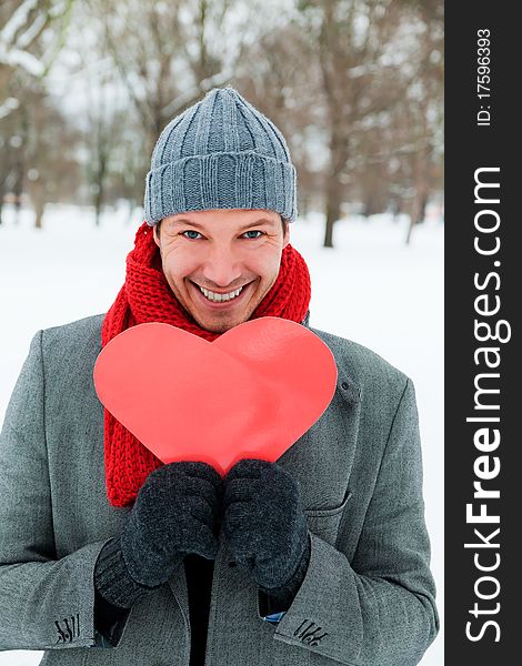 Man in love with heart standing on snow winter park. Man in love with heart standing on snow winter park