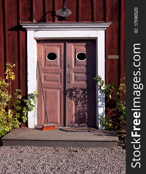 An old door with a brush on a wooden house. An old door with a brush on a wooden house.