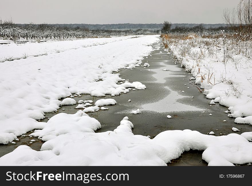 Frozen little river in winter filed