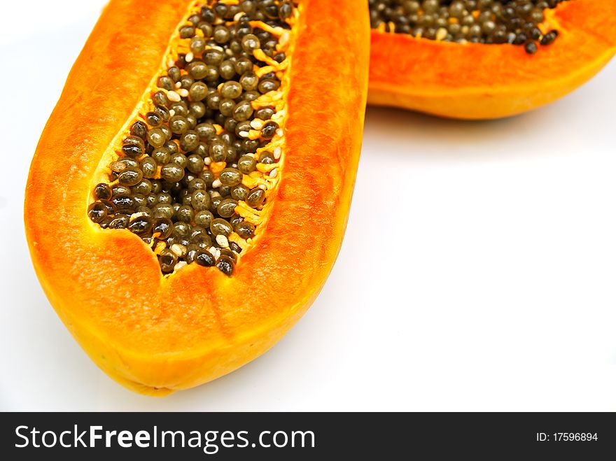 Halved papaya fruit on white background.