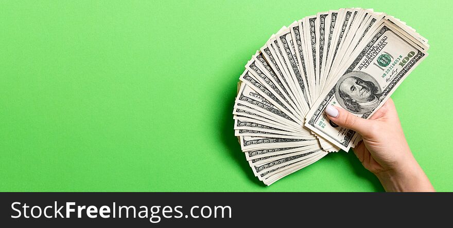 Top view of female hand holding a fan of one hundred dollars on colorful background. Loan concept. Prosperity concept with copy space.