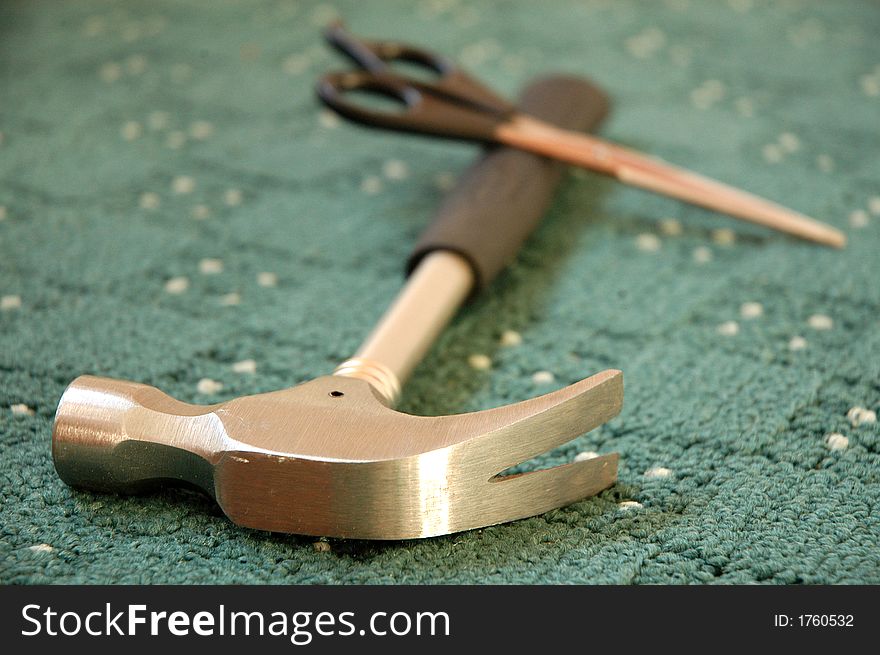 Scissors and hammer lying on new green carpet