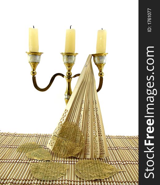 Beautiful candlestick, fan and leaf on a bamboo napkin. Beautiful candlestick, fan and leaf on a bamboo napkin