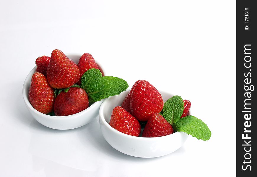 Two strawberry little bowls with mint on white background
