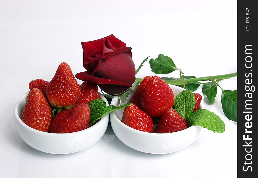 Two strawberry little bowls with mint on white background and one valentine rose