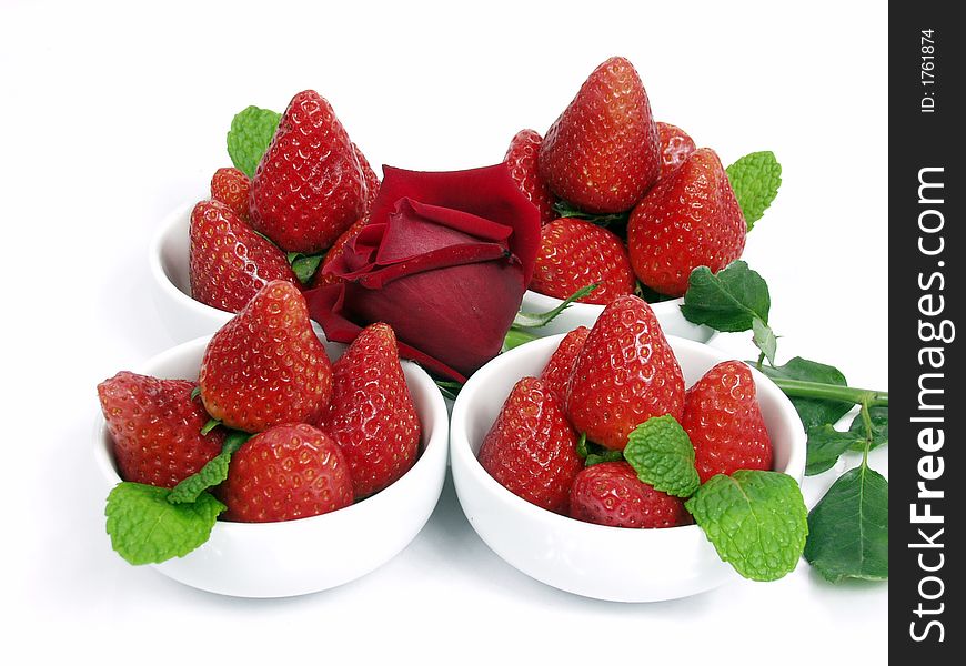 Some strawberry little bowls with mint on white background and one valentine rose