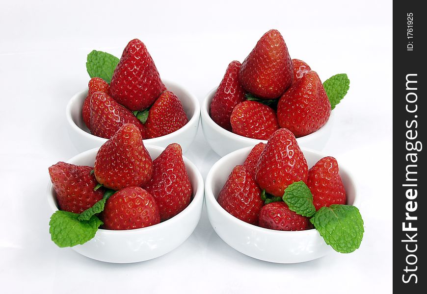 Some strawberry little bowls with mint on white background