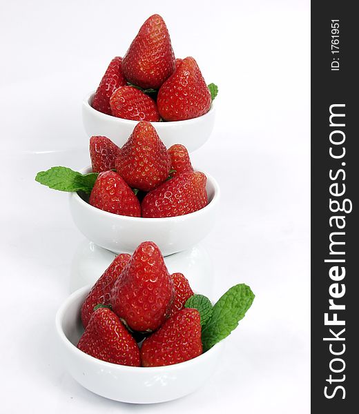 Some strawberry little bowls with mint on white background