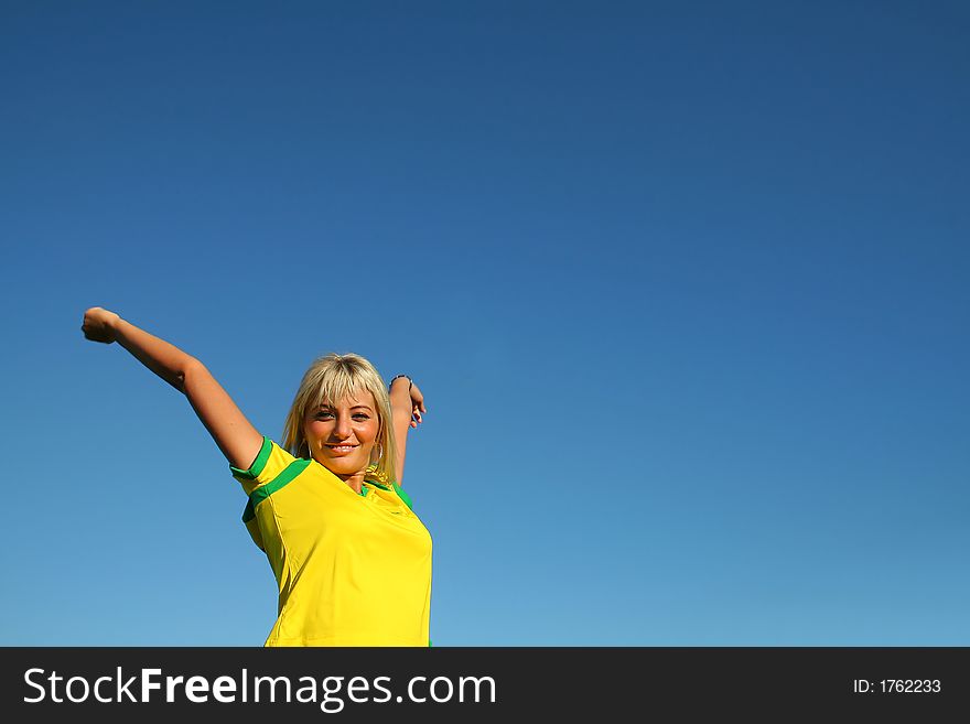 Sportive young blonde woman with yellow shirt, relaxing over a blue clear sky. Sportive young blonde woman with yellow shirt, relaxing over a blue clear sky