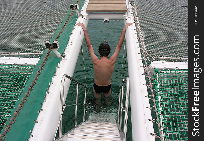 Snorkeling man at water on catamaran