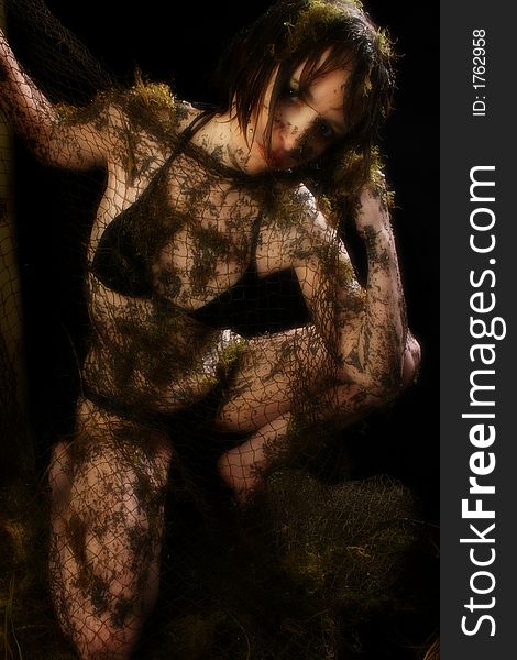 Woman covered in mud, moss and fishnet over black. Woman covered in mud, moss and fishnet over black.