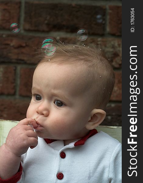 Image of baby boy sitting on a chair surrounded by soap bubbles. Image of baby boy sitting on a chair surrounded by soap bubbles