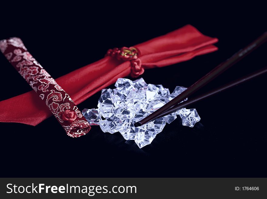 A pile of uncut diamonds on black satin with traditional chopsticks and oriental motif. A pile of uncut diamonds on black satin with traditional chopsticks and oriental motif