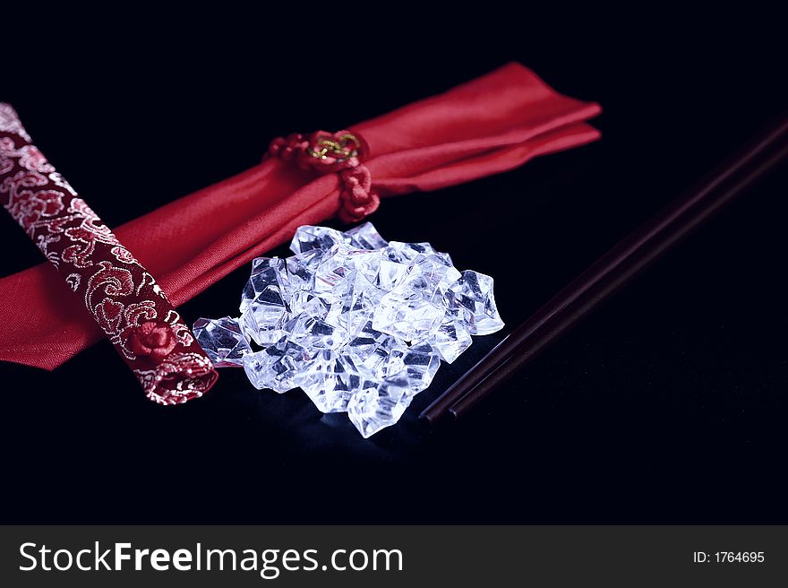 A pile of uncut diamonds on a black silk mat with chopsticks and an oriental flair. A pile of uncut diamonds on a black silk mat with chopsticks and an oriental flair.