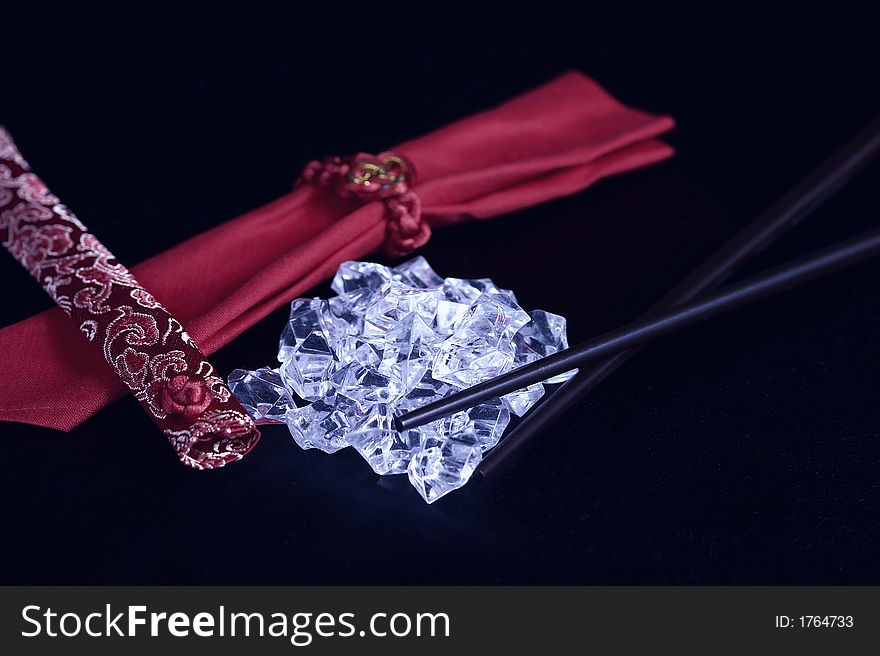 A pile of uncut diamonds on black silk with chopsticks and an oriental flair. A pile of uncut diamonds on black silk with chopsticks and an oriental flair