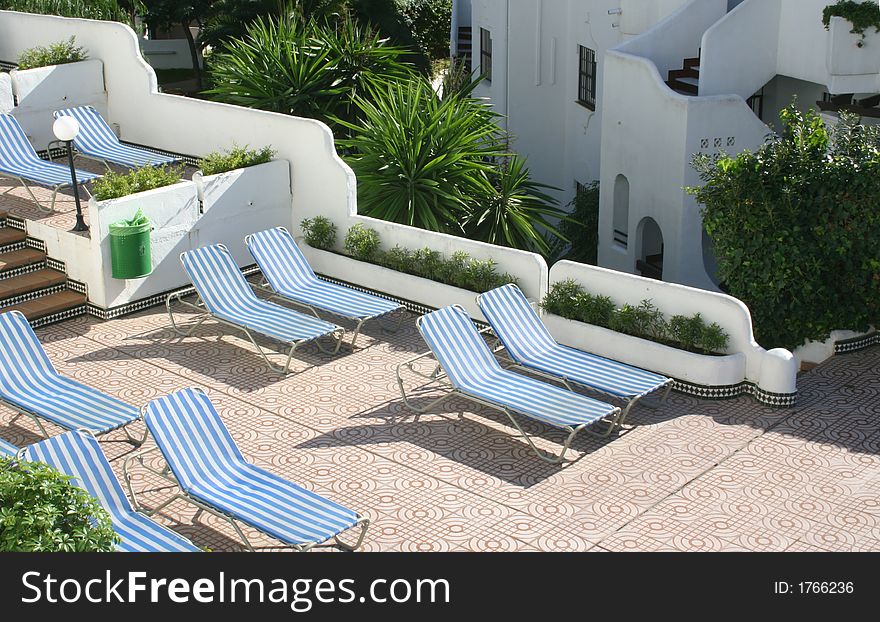 Sunlounges in pairs around the pool area of a hotel