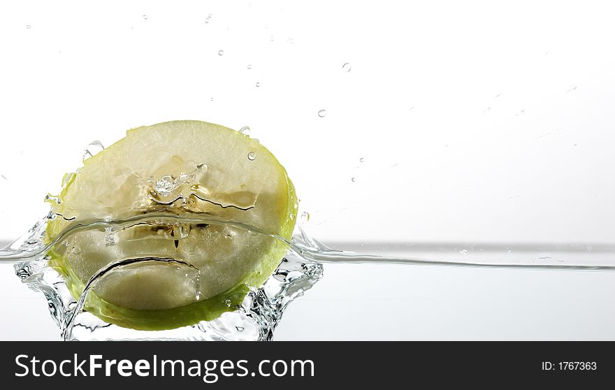 Green apple slice splashing into water. Green apple slice splashing into water