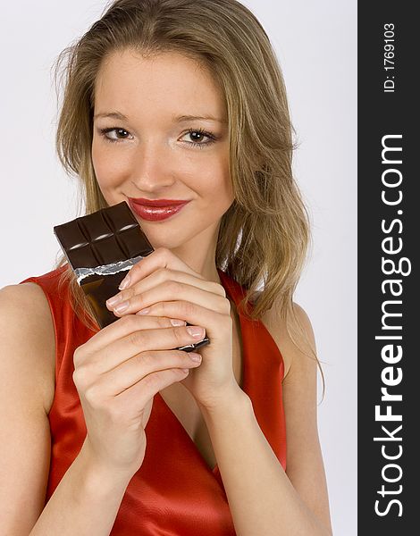 Young woman keeping bar of chocolate next to her mouth. Young woman keeping bar of chocolate next to her mouth.