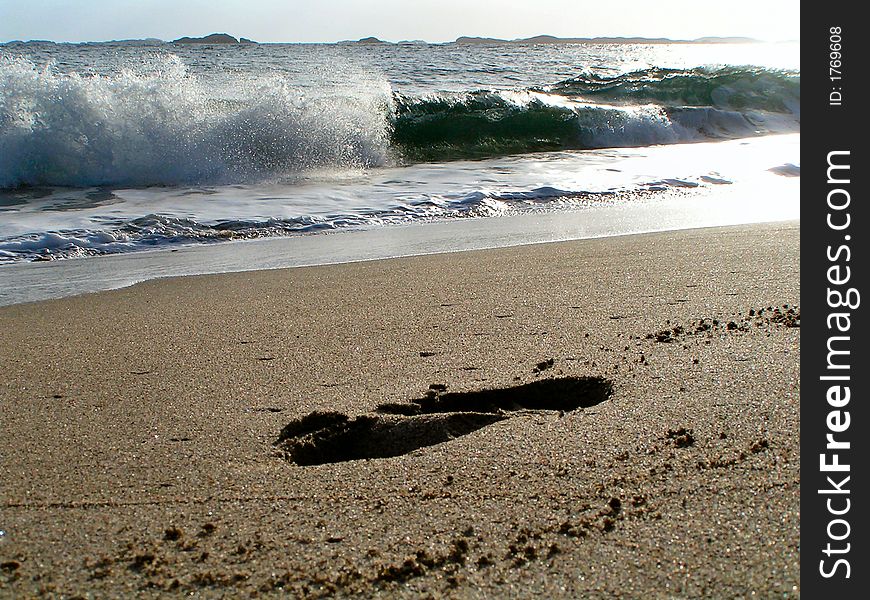 A deeply pressed in footprint on a sandy beach. A deeply pressed in footprint on a sandy beach