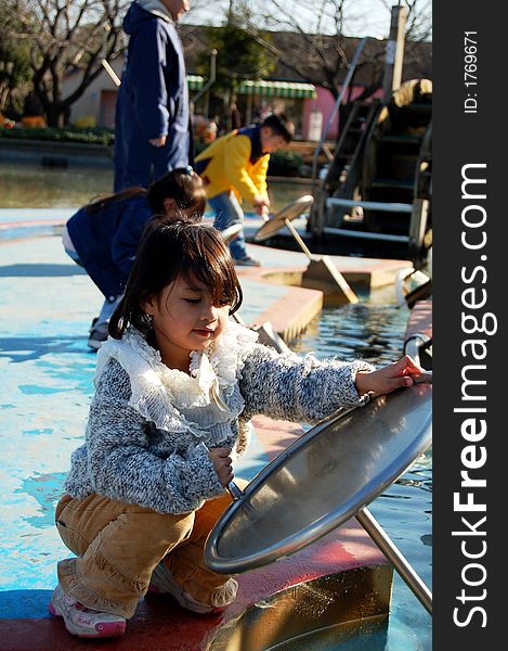 A young asian girl trying water pump at recreation park. A young asian girl trying water pump at recreation park.