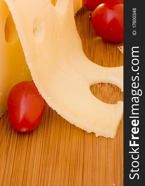 Swiss cheese slice and red tomato on a wood desk.