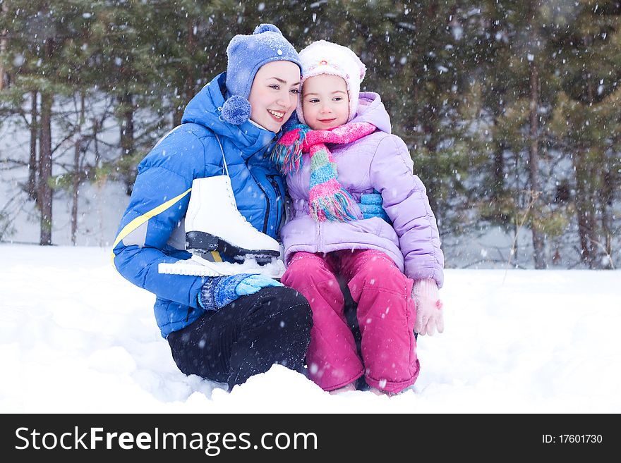 Happy mother and daughter, the family for a walk in a winter park, luge, skiing, skating, snowballs. Happy mother and daughter, the family for a walk in a winter park, luge, skiing, skating, snowballs