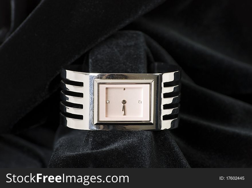 A horizontal image of a ladies wrist watch with pink rectangle face isolated against a black velvet backdrop. A horizontal image of a ladies wrist watch with pink rectangle face isolated against a black velvet backdrop