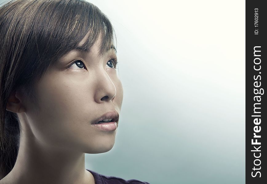 Studio photo of pretty young woman looking up