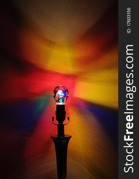 A colorful lightbulb with painted rainbow colors projecting onto the wall behind it with copyspace with room for your text. A colorful lightbulb with painted rainbow colors projecting onto the wall behind it with copyspace with room for your text