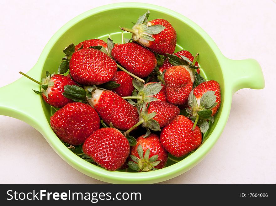 Ripe red strawberries in a green bowl