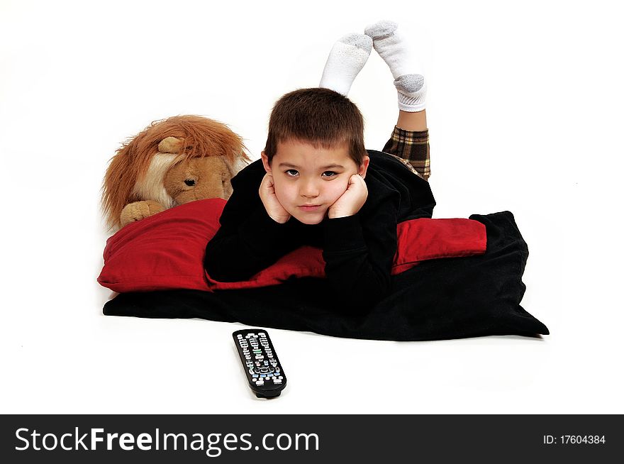 Young boy lounging on pillows on the floor propped up with hands, watching television. Young boy lounging on pillows on the floor propped up with hands, watching television