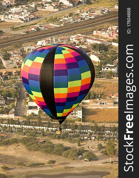 Multi color hot air balloon in flight with city in background