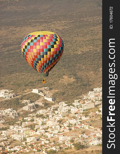 Multi color hot air balloon in flight with city in background