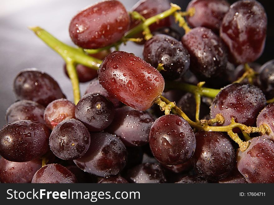 A close up of a cluster of grapes, wet and red. A close up of a cluster of grapes, wet and red