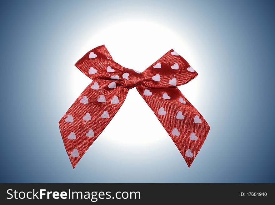 A close up of red bow with white hearts on a blue background