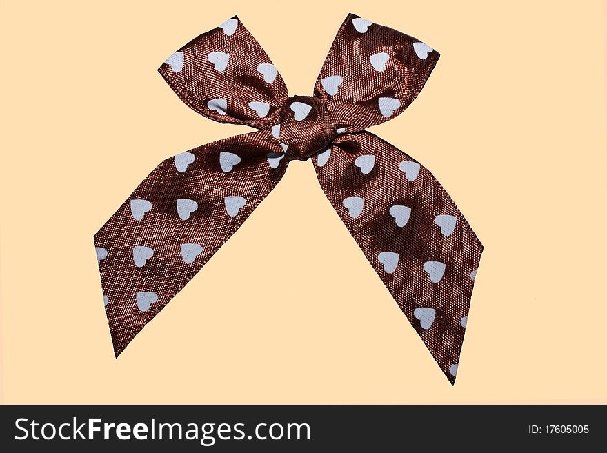 A close up of a brown satin bow with hearts on it