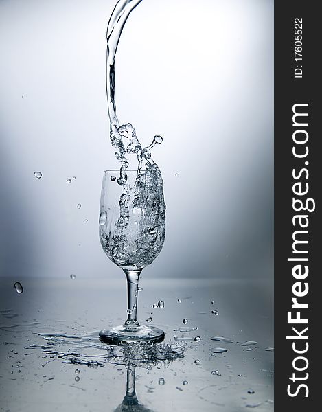 A nice dramatic capture of water pouring into a glass from high above, with some nice splashes below. A nice dramatic capture of water pouring into a glass from high above, with some nice splashes below.