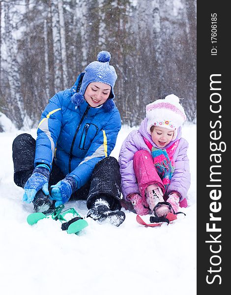 Happy mother and daughter, the family for a walk in a winter park, luge, skiing, skating, snowballs. Happy mother and daughter, the family for a walk in a winter park, luge, skiing, skating, snowballs