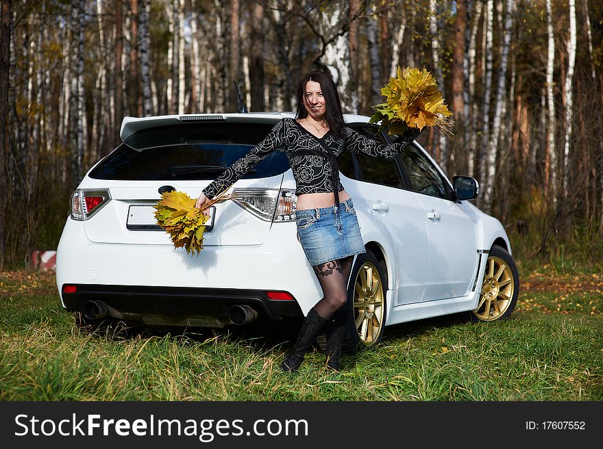 Beauty joyful girl with yellow leaves and white stylish modern car on nature in autumn park. Beauty joyful girl with yellow leaves and white stylish modern car on nature in autumn park