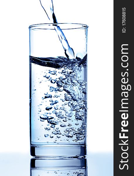 The water flowing in a glass.Dark blue toning. The water flowing in a glass.Dark blue toning