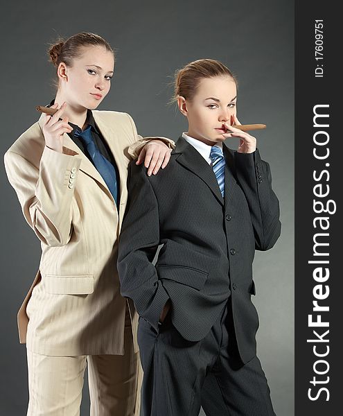 Two young girls with a cigar in man's suits. Two young girls with a cigar in man's suits