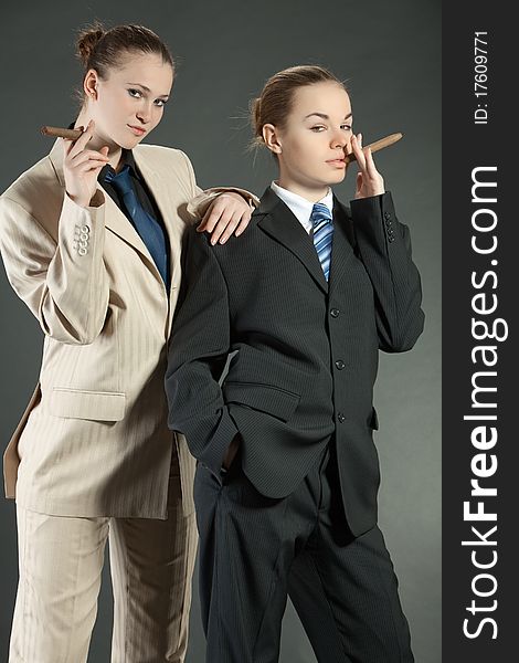 Two young girls with a cigar in man's suits. Two young girls with a cigar in man's suits