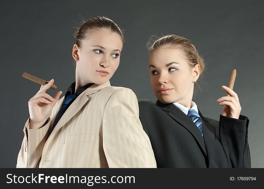 Two young girls with a cigar in man's suits. Two young girls with a cigar in man's suits