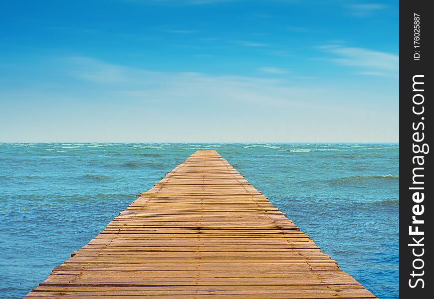 View of seascape with wooden walkway leading to the blue sea and beautiful cloudy skies. View of seascape with wooden walkway leading to the blue sea and beautiful cloudy skies