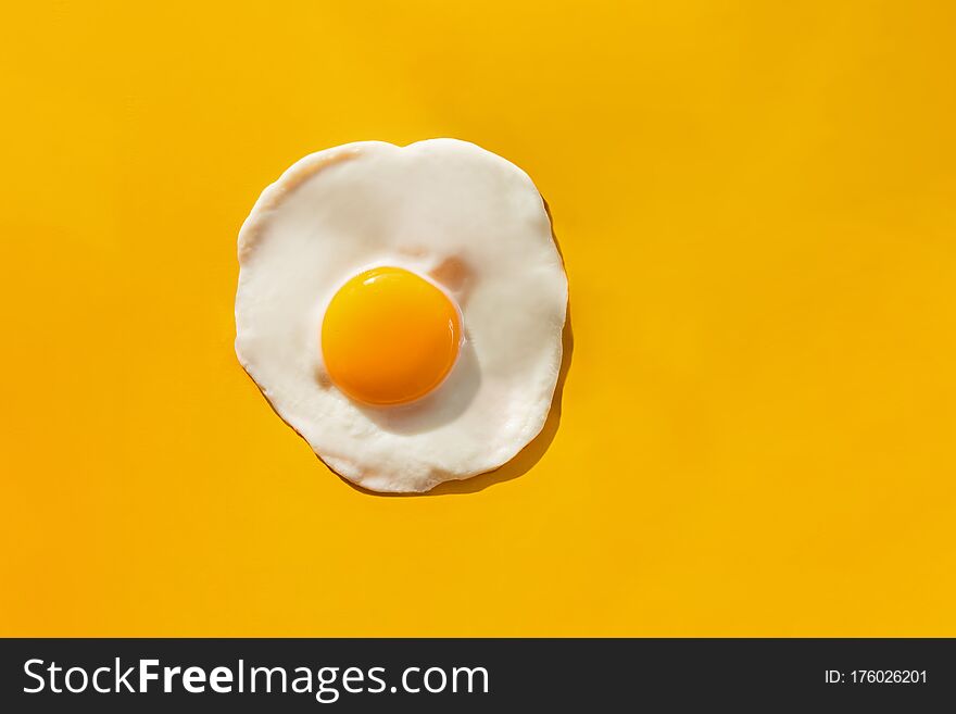 Fried egg on yellow background, top view